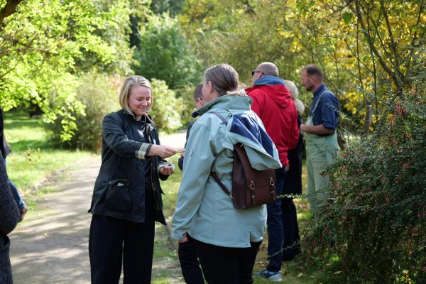 Mehrere Personen stehen im Wald und tauschen sich im Rahmen einer geführten Exkursion aus.