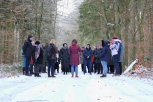 Gruppe von etwa 20 Personen bei einer Exkursion während der Zwischenbegutachtung der One-Health-Region Vorpommern, stehend auf einem verschneiten Waldweg und im Gespräch miteinander.